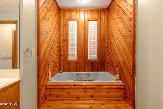 2324 Raintree Pl, Lynn Haven, FL 32444 - bathroom featuring a textured ceiling, a garden tub, wooden walls, vanity, and wood finished floors