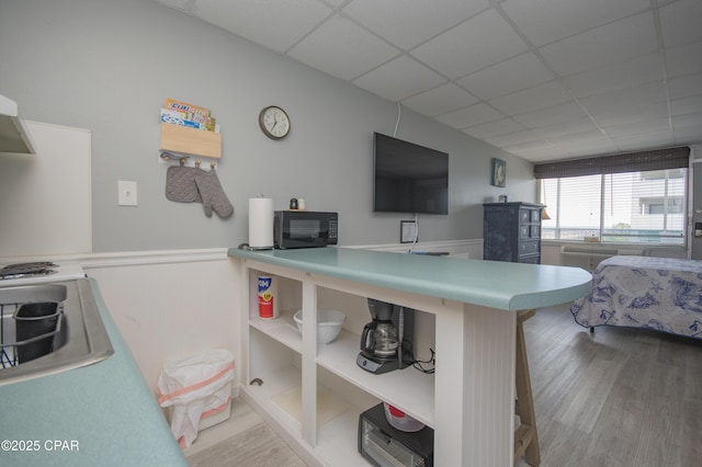 14401 Front Beach Rd Unit 206, Panama City Beach, FL 32413 - kitchen with black microwave, wood finished floors, a drop ceiling, and a wainscoted wall