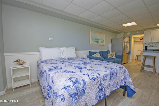 14401 Front Beach Rd Unit 206, Panama City Beach, FL 32413 - bedroom with freestanding refrigerator, light wood-type flooring, a drop ceiling, a wainscoted wall, and a walk in closet