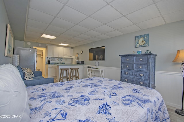 14401 Front Beach Rd Unit 206, Panama City Beach, FL 32413 - bedroom featuring a paneled ceiling, a wainscoted wall, light wood-type flooring, and freestanding refrigerator