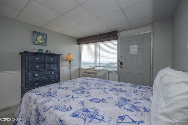 14401 Front Beach Rd Unit 206, Panama City Beach, FL 32413 - bedroom with wood finished floors, a drop ceiling, a wall unit AC, and a wainscoted wall