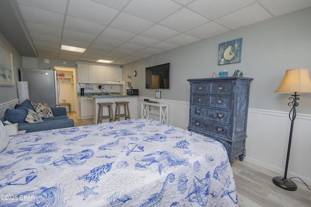 14401 Front Beach Rd Unit 206, Panama City Beach, FL 32413 - bedroom with freestanding refrigerator, light wood-type flooring, a paneled ceiling, and a wainscoted wall