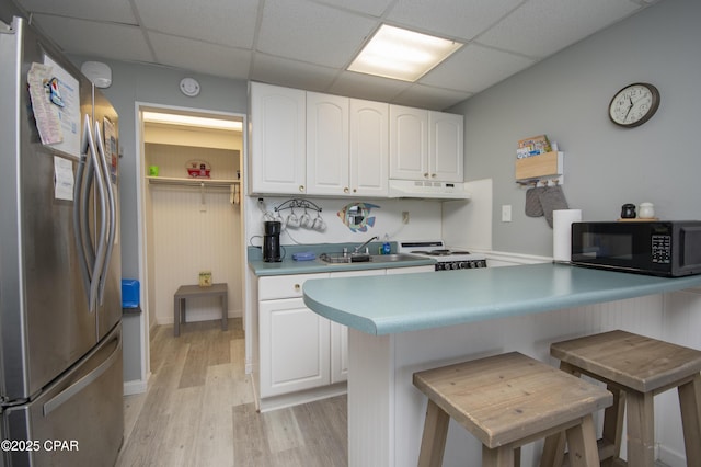 14401 Front Beach Rd Unit 206, Panama City Beach, FL 32413 - kitchen featuring freestanding refrigerator, black microwave, under cabinet range hood, a paneled ceiling, and white cabinets