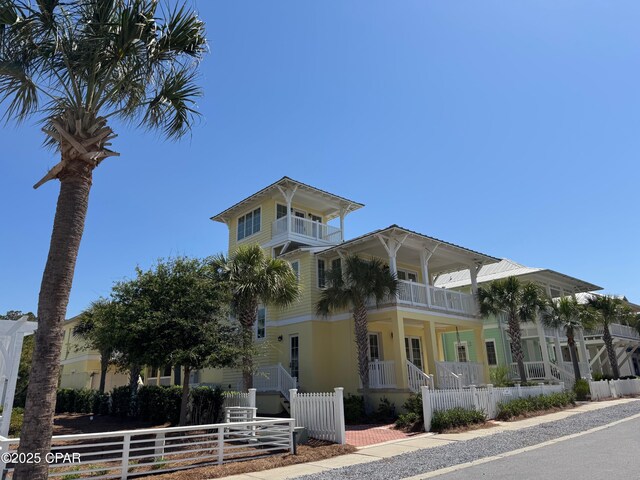 view of front of home featuring a balcony, a fenced front yard, and a porch