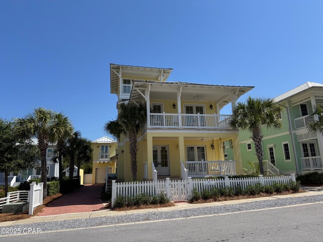 view of front facade with a fenced front yard, a balcony, french doors, and a porch