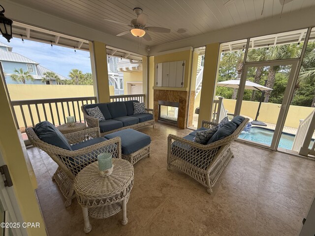 sunroom / solarium featuring ceiling fan and an outdoor living space with a fireplace