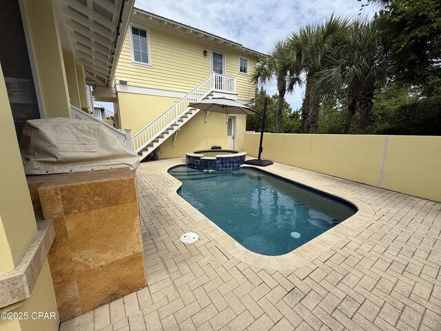 view of swimming pool with a pool with connected hot tub, a patio area, fence, central air condition unit, and stairway
