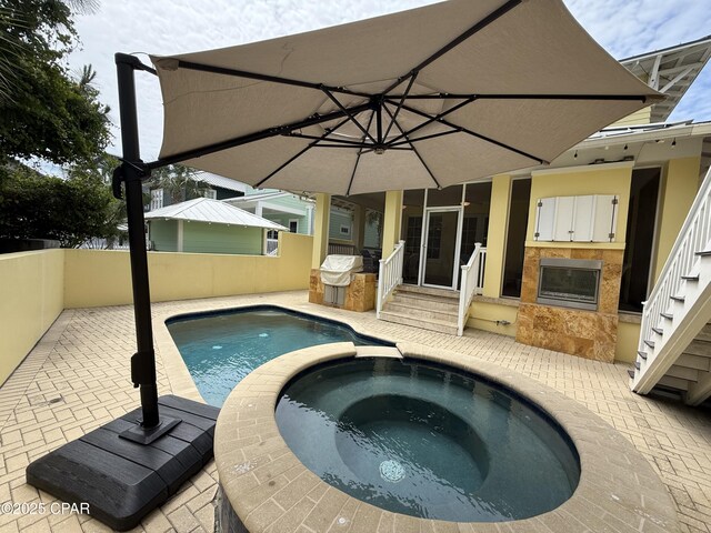 view of pool with a patio, fence, entry steps, and a pool with connected hot tub