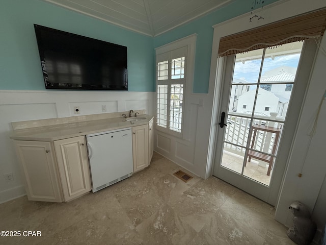 kitchen with a wainscoted wall, a decorative wall, refrigerator, light countertops, and dishwasher