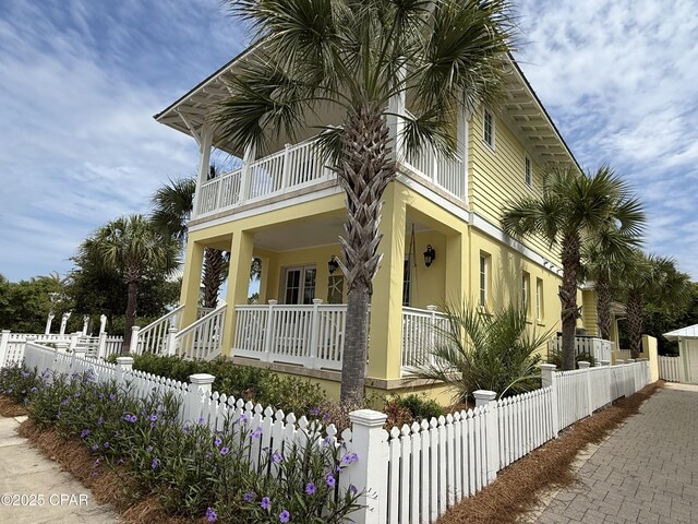 view of property exterior with covered porch, a balcony, a fenced front yard, and stucco siding
