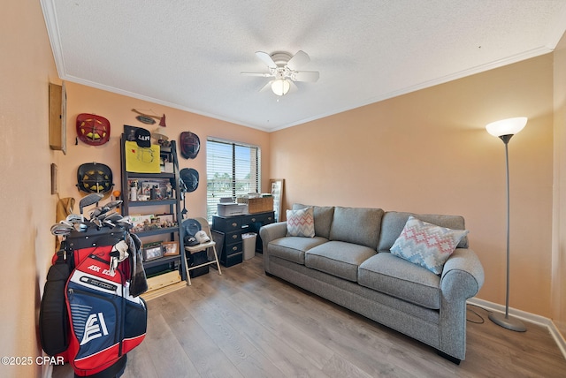 living room with ceiling fan, wood finished floors, crown molding, a textured ceiling, and baseboards