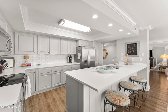 6905 Thomas Dr Unit 807, Panama City Beach, FL 32408 - kitchen with appliances with stainless steel finishes, a sink, ornamental molding, a kitchen breakfast bar, and light wood-style flooring