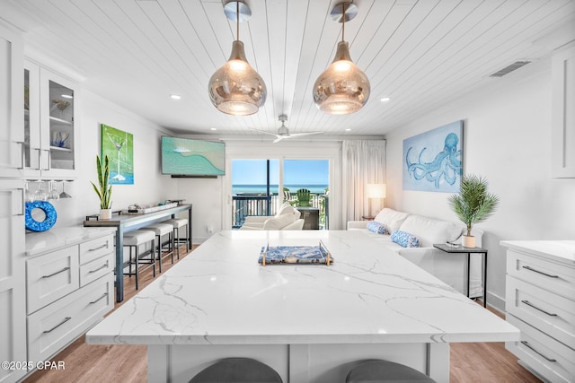 17735 Front Beach Rd Unit 4, Panama City Beach, FL 32413 - kitchen with wooden ceiling, light wood-type flooring, white cabinets, a kitchen bar, and a kitchen island