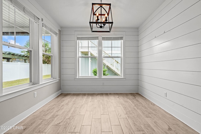 3104 Heartleaf E Ave, Panama City, FL 32405 - spare room with plenty of natural light, a chandelier, light wood-type flooring, wooden walls, and baseboards