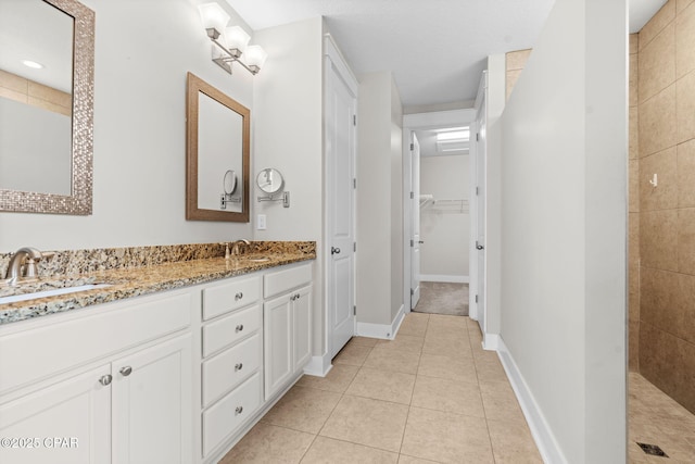 3104 Heartleaf E Ave, Panama City, FL 32405 - bathroom with tile patterned floors, double vanity, a tile shower, a walk in closet, and baseboards