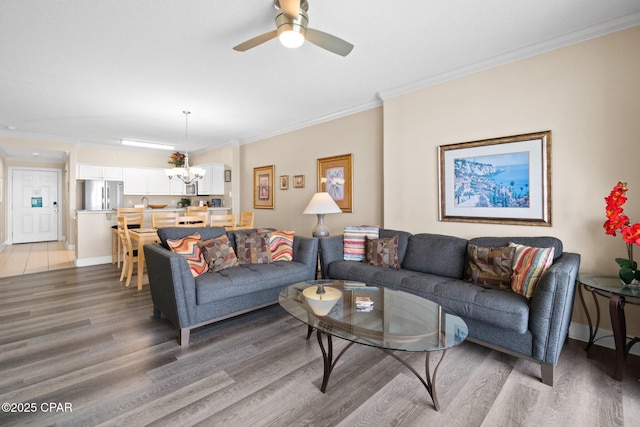 17545 Front Beach Rd Unit 1705, Panama City Beach, FL 32413 - living room with light wood-style floors, a chandelier, a ceiling fan, ornamental molding, and baseboards