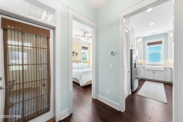corridor with a sink, baseboards, dark wood-type flooring, and recessed lighting