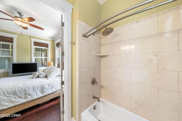 ensuite bathroom with washtub / shower combination, ceiling fan, wood finished floors, and ornamental molding