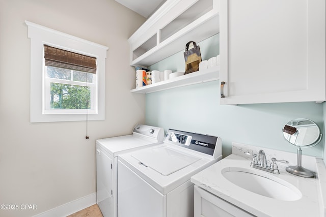 washroom featuring a sink, washer and dryer, and baseboards