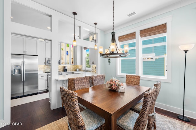 dining area with dark wood-style floors, a chandelier, and baseboards