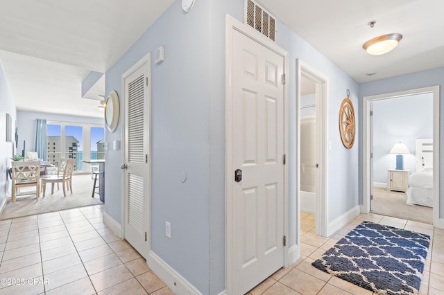 corridor with light tile patterned flooring and baseboards