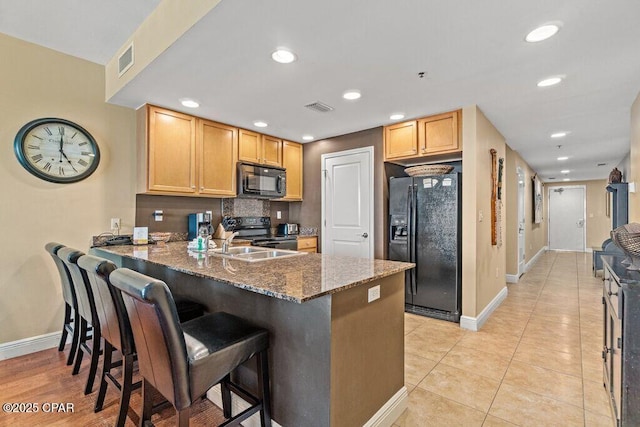 16701 Front Beach Rd Unit 306, Panama City Beach, FL 32413 - kitchen featuring black appliances, baseboards, dark stone counters, a peninsula, and recessed lighting
