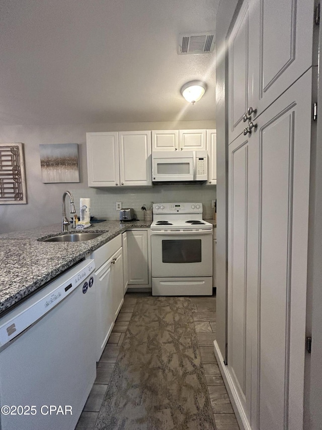 kitchen with white appliances, a sink, white cabinets, and light stone countertops