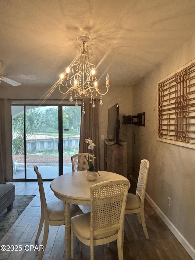 dining space featuring wood finished floors, a chandelier, baseboards, and a ceiling fan