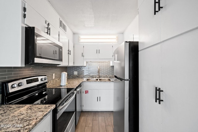 8743 Thomas Dr Unit 1211, Panama City Beach, FL 32408 - kitchen with stainless steel appliances, a sink, decorative backsplash, and white cabinets