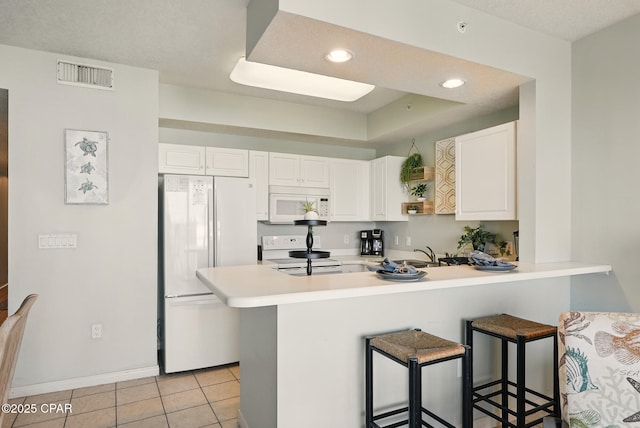 1515 SE Miracle Strip Pkwy Unit 609, Fort Walton Beach, FL 32548 - kitchen with white appliances, a peninsula, a kitchen breakfast bar, light countertops, and white cabinets