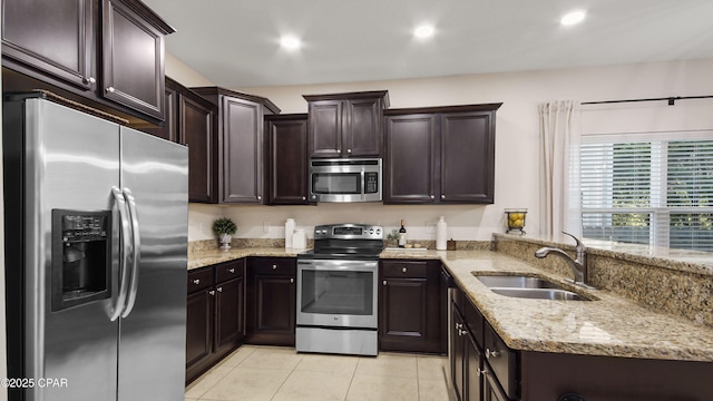 76 Mosaic Oaks Cir, Santa Rosa Beach, FL 32459 - kitchen featuring stainless steel appliances, a sink, light tile patterned floors, light stone countertops, and dark brown cabinets