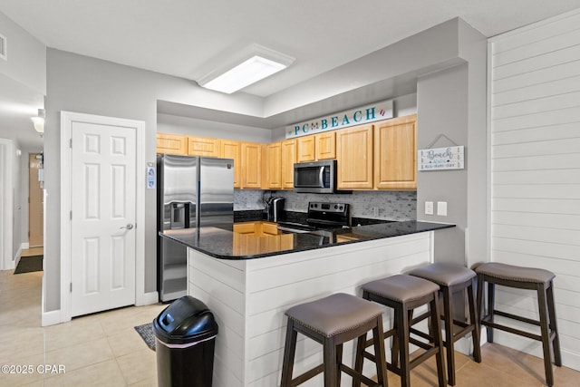 14825 Front Beach Rd Unit 2210, Panama City Beach, FL 32413 - kitchen with stainless steel appliances, light brown cabinetry, light tile patterned floors, dark countertops, and a peninsula