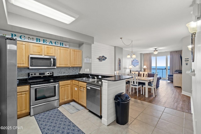 14825 Front Beach Rd Unit 2210, Panama City Beach, FL 32413 - kitchen featuring appliances with stainless steel finishes, a peninsula, dark countertops, a sink, and light tile patterned floors