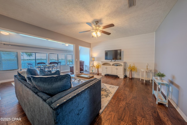 living area with a textured ceiling, a ceiling fan, dark wood-style floors, and baseboards