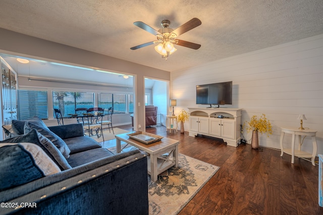 living area featuring a textured ceiling, a ceiling fan, dark wood-style floors, and baseboards