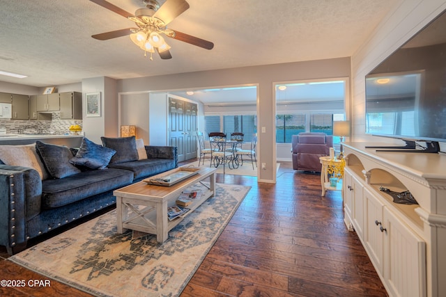 living room featuring a textured ceiling, ceiling fan, dark wood-style floors, and baseboards