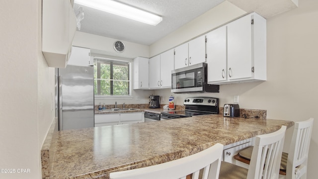 kitchen with appliances with stainless steel finishes, a sink, a peninsula, white cabinets, and a kitchen breakfast bar
