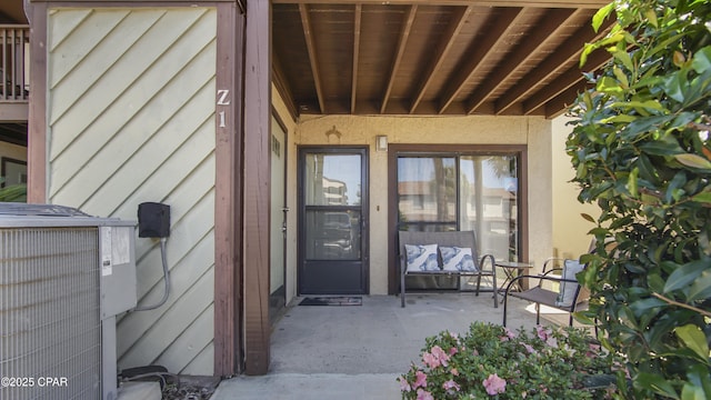 view of exterior entry featuring central AC and stucco siding