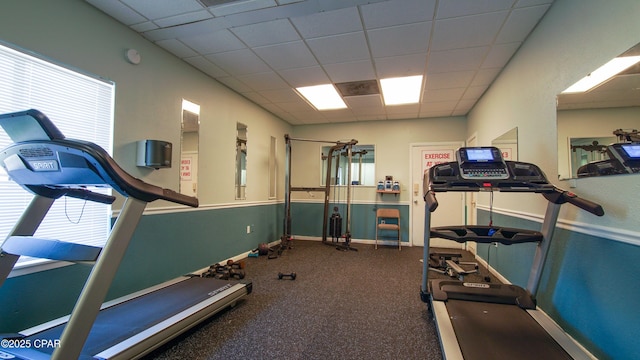 exercise room featuring a drop ceiling and baseboards