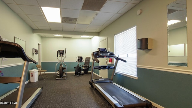 workout area featuring a drop ceiling and baseboards