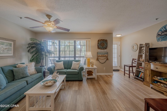living area featuring a textured ceiling, ceiling fan, light wood-style floors, and baseboards