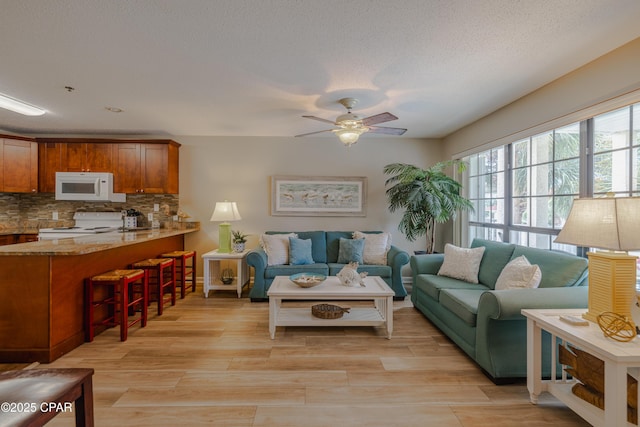 living area with ceiling fan and light wood-type flooring