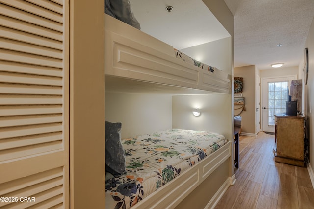 bedroom with light wood-style flooring, baseboards, and a textured ceiling