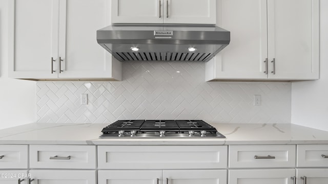 kitchen with ventilation hood, stainless steel gas cooktop, white cabinetry, and tasteful backsplash