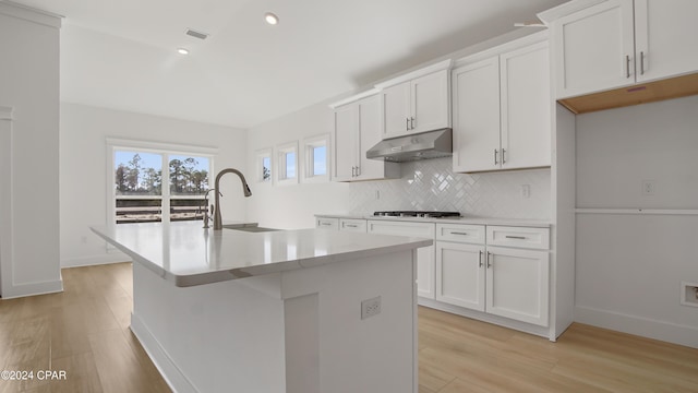 kitchen with a sink, under cabinet range hood, gas cooktop, light wood-style flooring, and recessed lighting