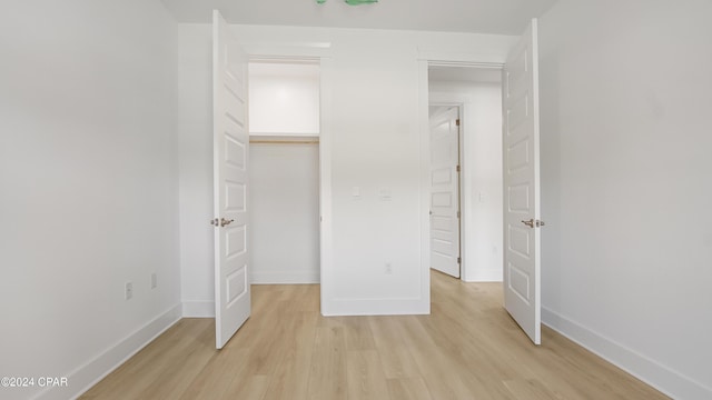 unfurnished bedroom featuring light wood finished floors, baseboards, and a closet