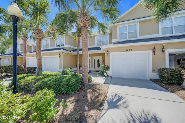 view of property with stucco siding, an attached garage, and driveway