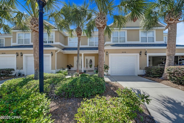 townhome / multi-family property featuring stucco siding, an attached garage, and driveway