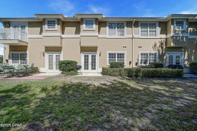 back of house with french doors, stucco siding, and a yard
