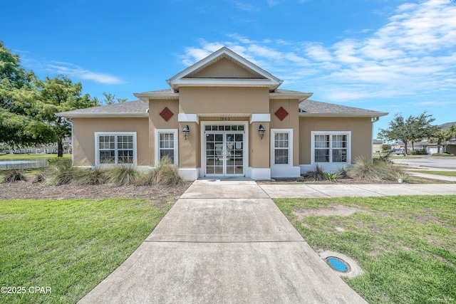 view of front facade featuring french doors, stucco siding, and a front lawn